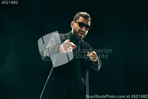 Image of The barded man in a suit at black studio