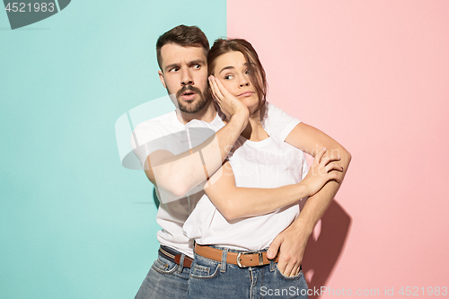 Image of Wow. Doubtful pensive couple with thoughtful expression making choice against pink background