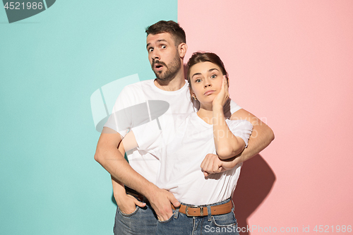 Image of Wow. Doubtful pensive couple with thoughtful expression making choice against pink background