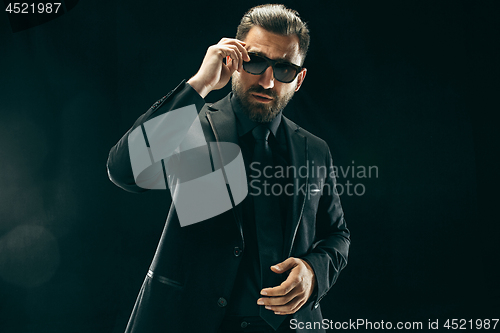 Image of The barded man in a suit at black studio