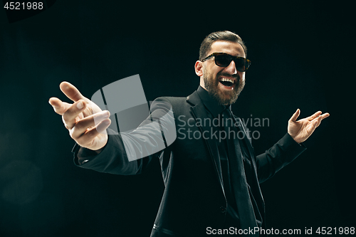 Image of The barded man in a suit at black studio