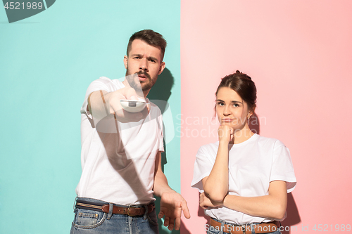 Image of Couple bored watching tv with a the hand holding the remote control standing at studio