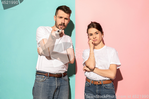 Image of Couple bored watching tv with a the hand holding the remote control standing at studio