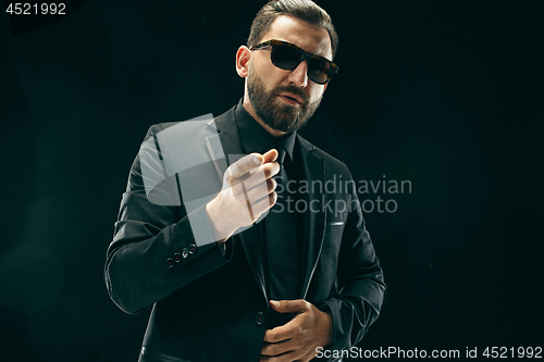 Image of The barded man in a suit at black studio