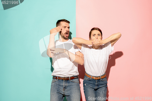 Image of Closeup portrait of young couple, man, woman. TV fan concept on pink and blue background. Emotion contrasts