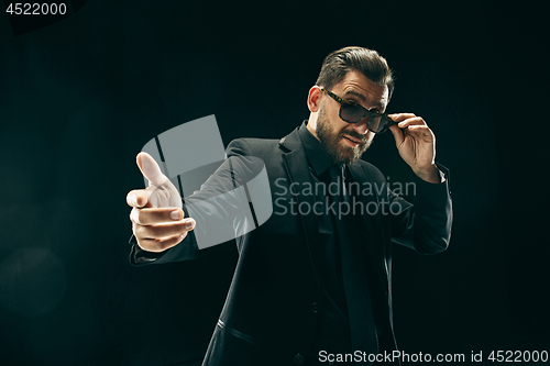 Image of The barded man in a suit at black studio