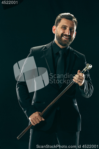 Image of The barded man in a suit holding cane.