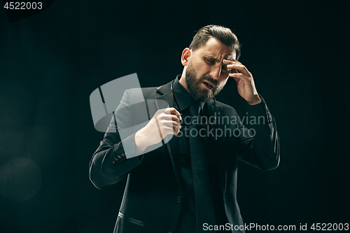 Image of The barded man in a suit at black studio