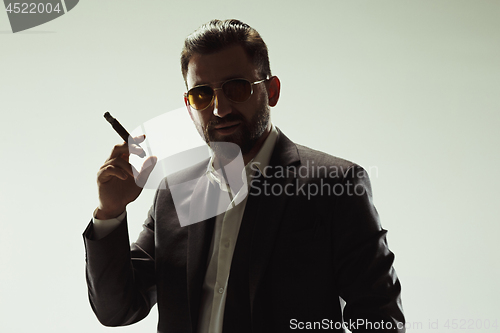 Image of The barded man in a suit holding cigar