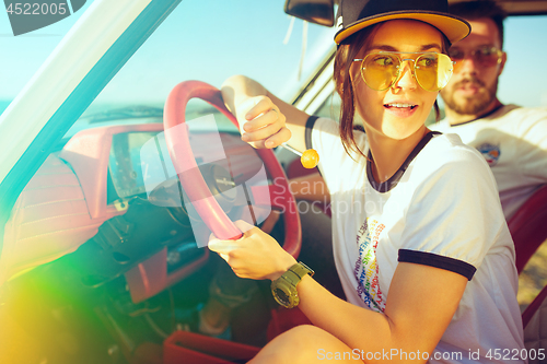 Image of Laughing romantic couple sitting in car while out on a road trip at summer day