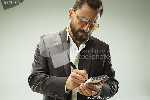 Image of Male beauty concept. Portrait of a fashionable young man with stylish haircut wearing trendy suit posing over gray background.