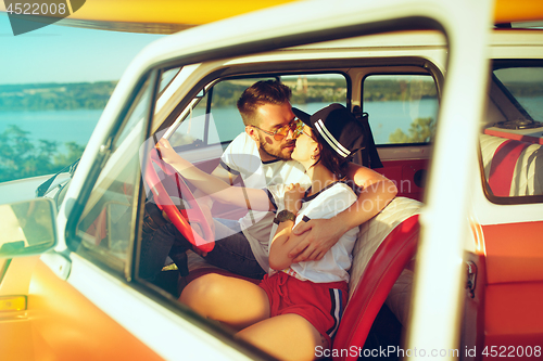 Image of Laughing romantic couple sitting in car while out on a road trip at summer day