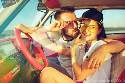Image of Laughing romantic couple sitting in car while out on a road trip at summer day