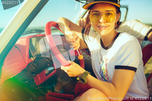 Image of Laughing romantic couple sitting in car while out on a road trip at summer day