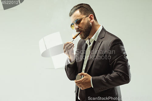 Image of The barded man in a suit holding cigar