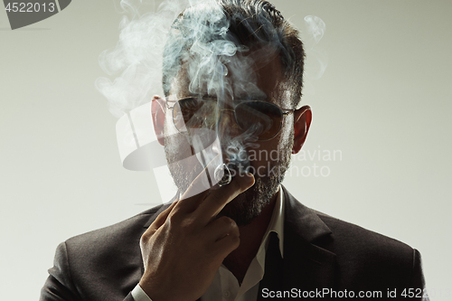 Image of The barded man in a suit holding cigar