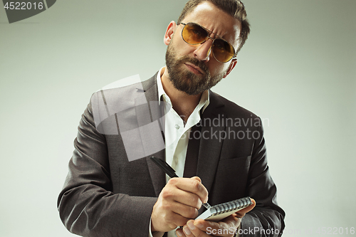 Image of Male beauty concept. Portrait of a fashionable young man with stylish haircut wearing trendy suit posing over gray background.