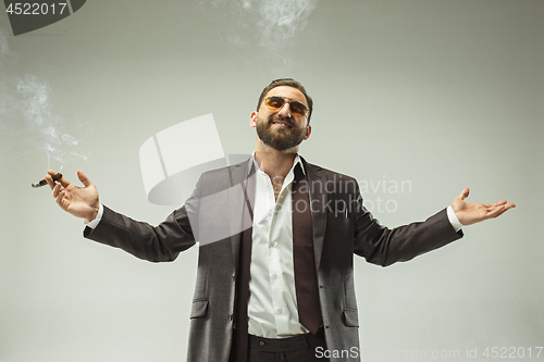 Image of The barded man in a suit holding cigar