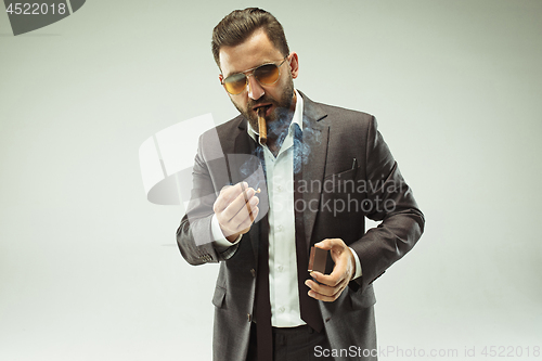 Image of The barded man in a suit holding cigar