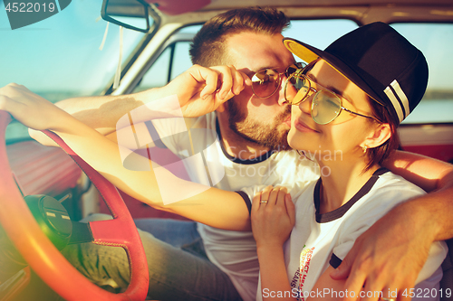 Image of Laughing romantic couple sitting in car while out on a road trip at summer day