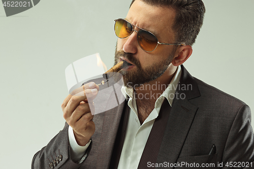 Image of The barded man in a suit holding cigar