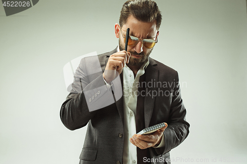 Image of Male beauty concept. Portrait of a fashionable young man with stylish haircut wearing trendy suit posing over gray background.