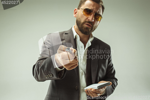 Image of Male beauty concept. Portrait of a fashionable young man with stylish haircut wearing trendy suit posing over gray background.