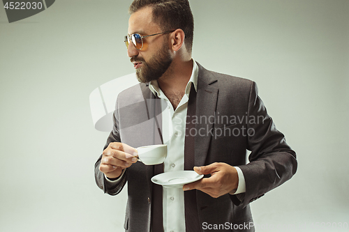 Image of Male beauty concept. Portrait of a fashionable young man with stylish haircut wearing trendy suit posing over gray background.