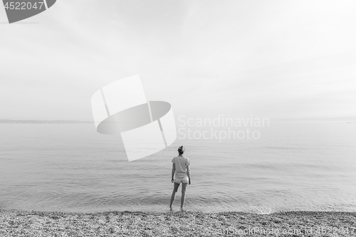 Image of Happy Carefree Woman Enjoying Sunset Walk on White Pabbled Beach.