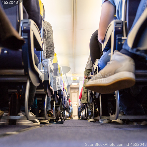 Image of Low agle view of passenegers commercial airplane aisle with passenegers sitting on their seats while flying