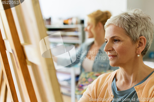 Image of senior woman drawing on easel at art school studio