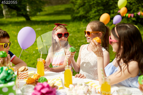 Image of kids eating cupcakes on birthday party in summer