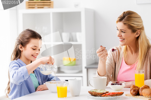 Image of happy mother and daughter having breakfast at home