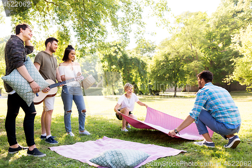 Image of friends arranging place for picnic at summer park