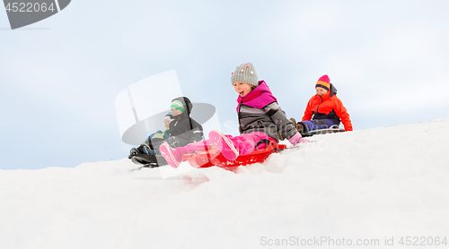 Image of kids sliding on sleds down snow hill in winter