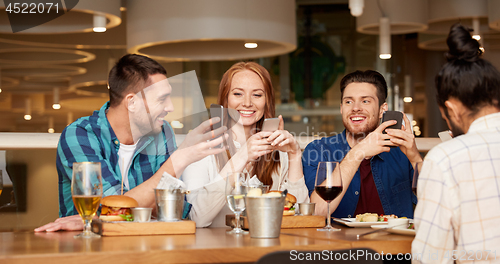 Image of happy friends with smartphones at restaurant