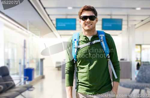 Image of smiling man with backpack over airport terminal