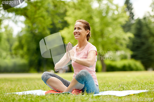 Image of happy woman meditating in summer park