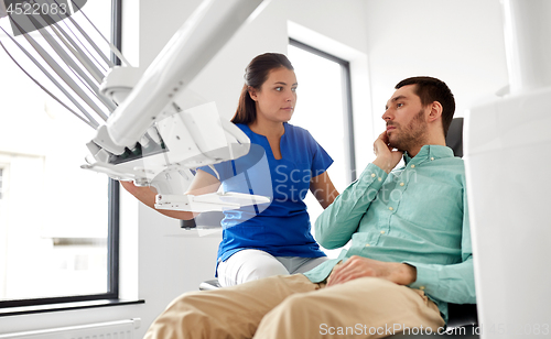 Image of man with toothache and dentist at dental clinic