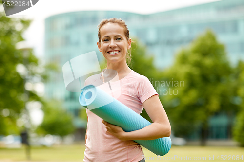 Image of happy smiling woman with exercise mat at city park