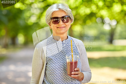 Image of senior woman drinking takeaway shake at park