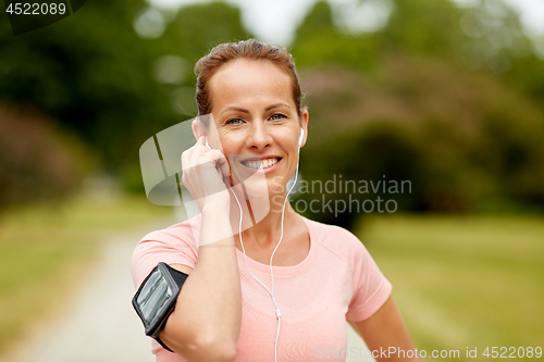 Image of woman with earphones listening to music at park