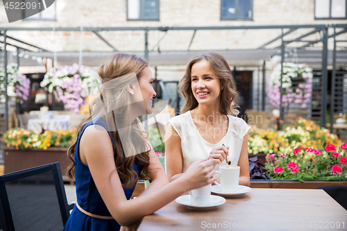 Image of smiling young women drinking coffee at street cafe