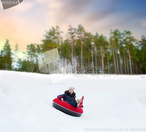 Image of happy teenage girl sliding down hill on snow tube