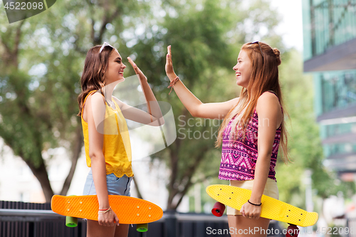 Image of teenage girls with skateboards making high five