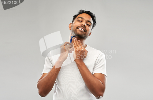 Image of indian man shaving beard with razor blade