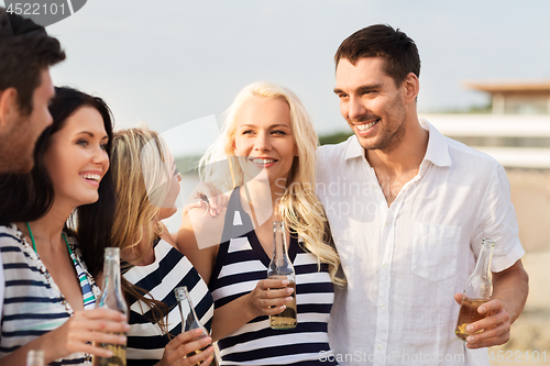 Image of happy friends drinking non alcoholic beer on beach