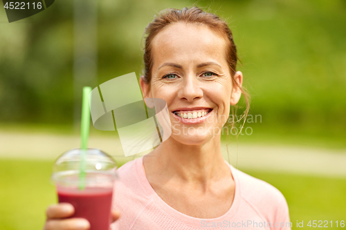 Image of woman drinking smoothie after exercising in park