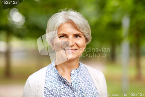 Image of portrait of happy senior woman at summer park