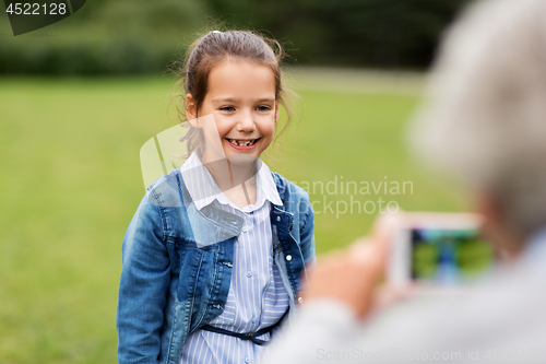 Image of little girl being photographed at summer park